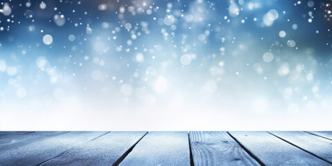 Winter snowy blurred defocused blue background and empty wooden flooring, flakes of snow fall and sparkle on light, copy space