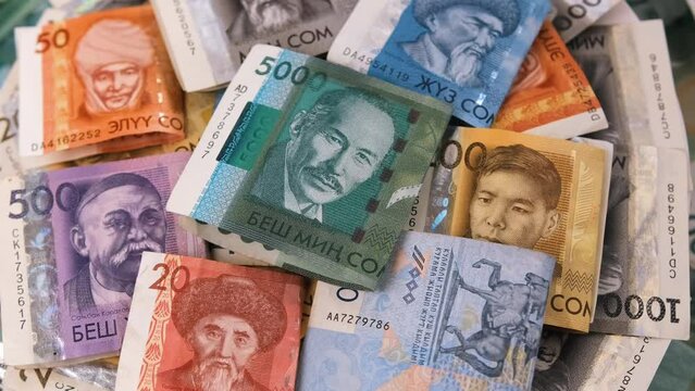 Paper bills pack Kyrgyz som different value on table close up. Many cash som money of Kyrgyzstan close-up tracking rotate background.