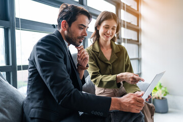 Two happy business woman and man using laptop working on computer at workplace. Cheerful young professional multiethnic colleagues team discussing online digital technology corporate project in office