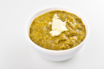 Sarson saag in bowl with white butter on white background