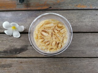 Iced coffee and flower on wood background
