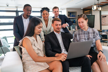 International professional business team people using laptop standing in office. Busy diverse workers group looking at computer discussing digital technology corporate strategy in teamwork at office.