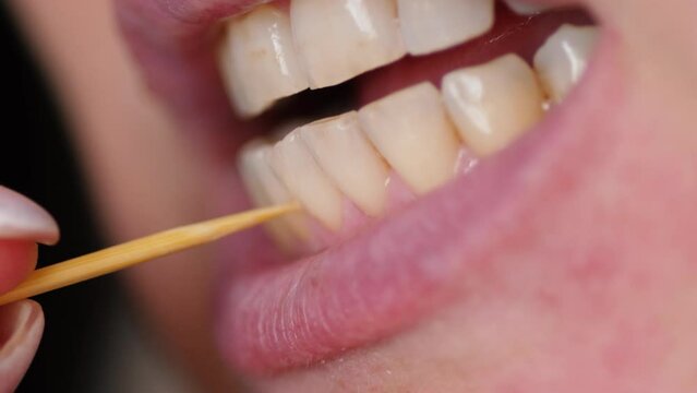 extreme close-up woman removes leftover food from her teeth with a wooden toothpick. , oral hygiene after eating.Selective focus.everyday hygiene