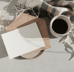 Card mockup, envelopes, cup of coffee, checkered scarf top view flatlay with copy space. Lifestyle Autumn background with sunlight shadow. Fall greeting card, invitation, blank.