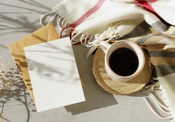 Card mockup, envelopes, cup of coffee, checkered scarf top view flatlay with copy space. Lifestyle Autumn background with sunlight shadow. Fall greeting card, invitation, blank.