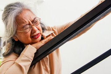 Asian elderly woman in frail health sick with acute heart disease walking up the stairs of the...