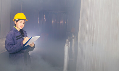 Female employee inspects the low temperature raw material storage room notes the room number...