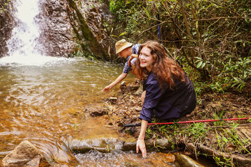 Nature hiking trip : Caucasian couple travel to Thailand's national parks during the summer relax in waterfalls, natural streams lush forests have fun enjoy hiking in the tropical mountains.