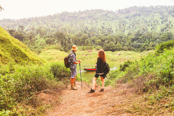 Obraz premium Two caucasian adventurer couples backpacking and watching passenger boat take tourists to the starting point for hiking nature studies, mountains waterfalls and rivers exciting hiking adventures. 