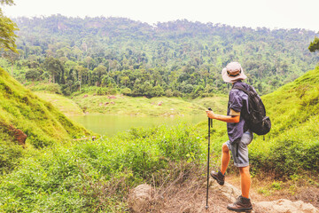 Back view young caucasian male adventurer backpacking hiking trip through Thailand's tropical forests standing looking at the sky mountains rivers and lush forests nature's beauty and fresh air.