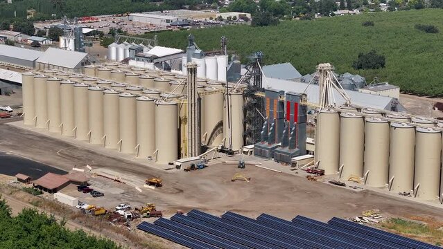 Aerial Sutter California rice grain elevator solar panels. Economy based on farming rice, grains, walnuts peaches and cattle ranch. Fields act as wetlands for waterfowl and birds.