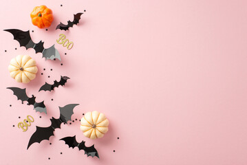Hauntingly delightful display: top view of tiny pumpkins, bones, bats, glittering text boo and black confetti on pastel pink surface, perfect for greetings or ads