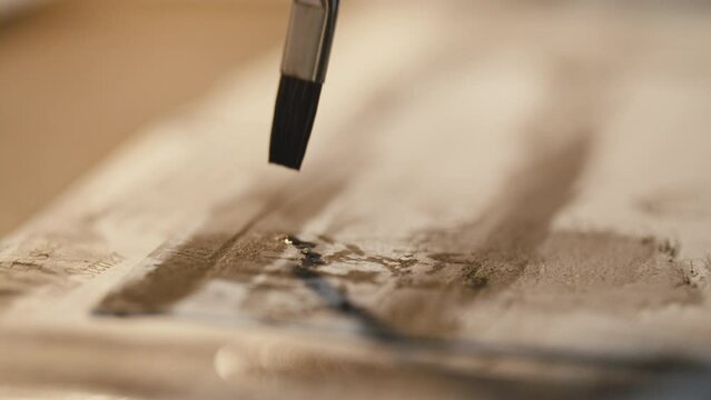 closeup of a small brush making little paint dots on white paper
