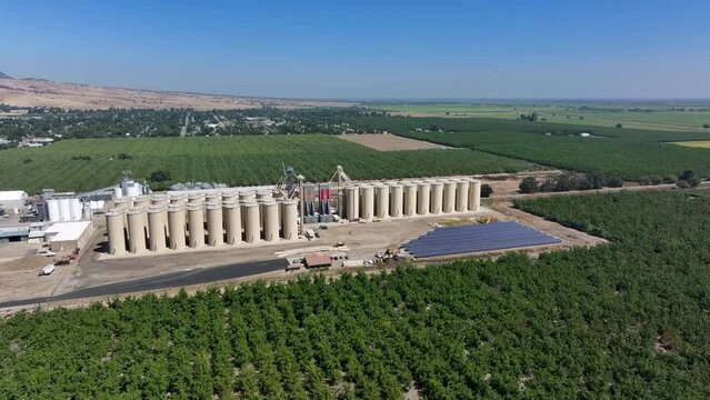 Aerial Sutter California rice grain elevator orchard solar panels circle. Economy based on farming rice, grains, walnuts peaches and cattle ranch. Fields act as wetlands for waterfowl and birds.