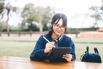 Young adult asian woman using digital tablet for digital nomad work and study