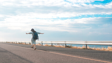 Rear view of young woman traveler with backpack freedom travel minimal background with blue sky