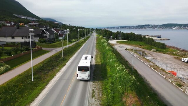 Bus transportation in Tromso on scenic road next to fjord, aerial tracking