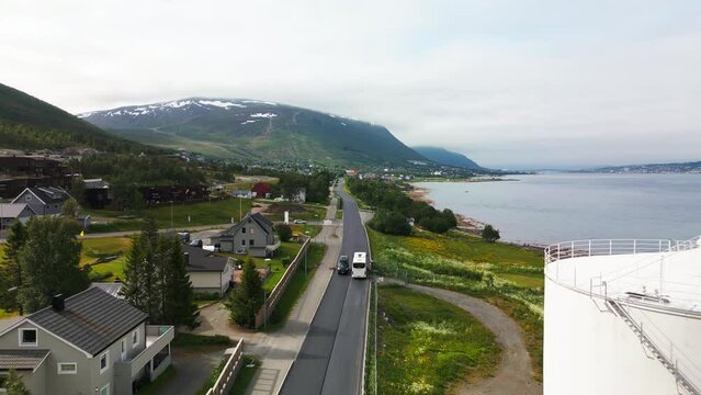 Drone tracking shot of white bus on scenic road next to fjord, Tromso, Norway