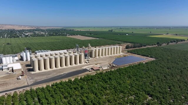 Aerial Sutter California rice grain elevator orchard solar panels circle fast. Economy based on farming rice, grains, walnuts peaches and cattle ranch. Fields act as wetlands for waterfowl and birds.