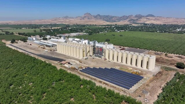 Aerial Sutter California rice grain elevator walnut orchard circle. Economy based on farming rice, grains, walnuts peaches and cattle ranch. Fields act as wetlands for waterfowl and birds.