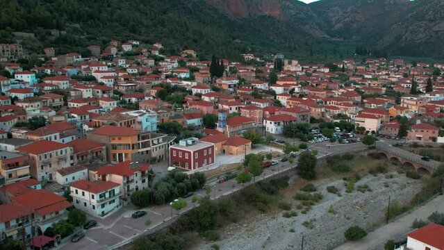 Dry riverbed and iconic red orange roofed homes vibrant colors in leonidio, greece, aerial