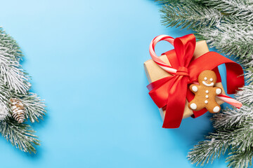 Christmas fir tree branch and gift box over blue