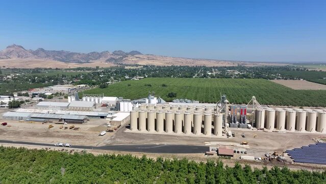 Aerial Sutter California rice grain elevator nut orchard pull 3. Economy based on farming rice, grains, walnuts peaches and cattle ranch. Fields act as wetlands for waterfowl and birds.