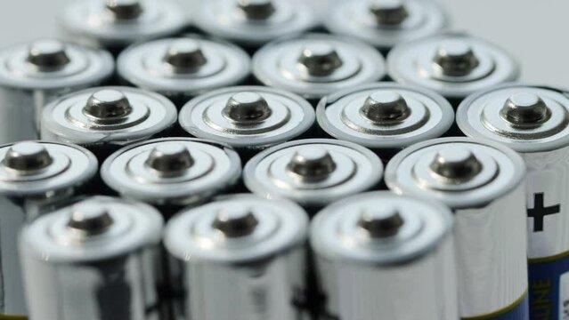 A lot of alkaline charged batteries with different polarity and power. Battery recycling, plus and minus, background. Rotation around its own axis. Macro