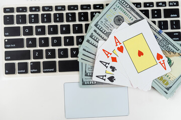 Poker playing card with dollar bills above computer keyboard