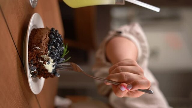 Close-up of woman eating blueberry tart with fork in cafe