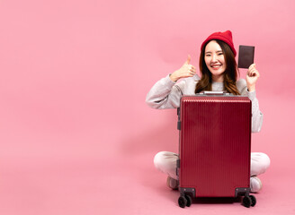Young Asian Woman Traveler with a Smile Gives Thumbs up. Enjoying a Happy Vacation Journey, Holding Her Passport in Pink Background Isolated. Representing the Joy of Travel and Adventure - obrazy, fototapety, plakaty