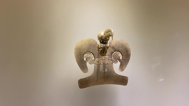 Pre-Columbian indigenous amulet object of pure gold exhibited in showcase in Bogota.