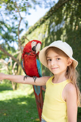 child girl with beautiful macaw parrot in her shoulder in the zoo, Bali, Indonesia.  © Julija