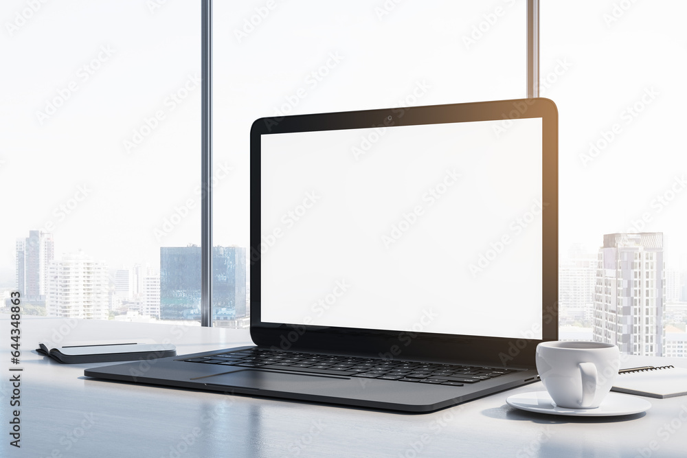 Poster Close up of laptop computer with empty white mock up monitor, coffee cup and notepad placed on desk. Window with bright city view in the background. 3D Rendering.