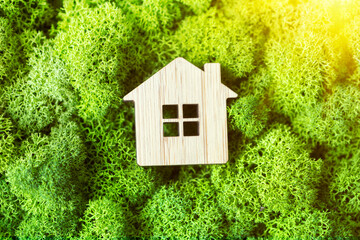 small toy house on a background of plants as a symbol of a private country house. The concept of real estate in mortgages. sunlight