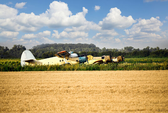 Old retro agricultural propeller double-wing airplanes on field. Landscape with cloudy sky