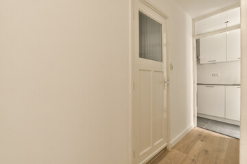 an empty room with white walls and wood flooring on the right side of the room, there is a door leading to another