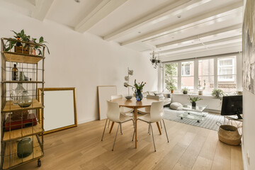 a living room with white walls and wood flooring the room is decorated with plants, furniture and...