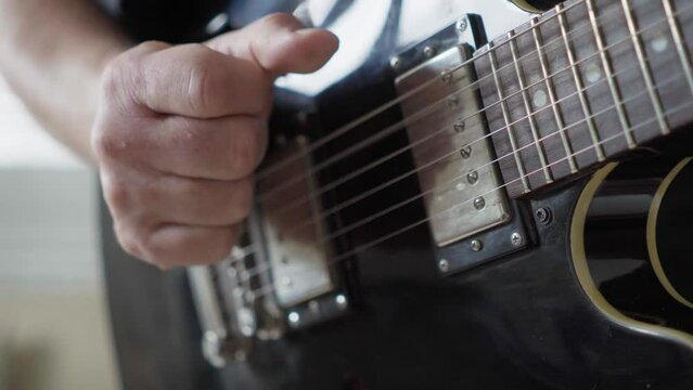 Close-up of a guitarist's right hand playing fingerstyle on an electric 335-style guitar.