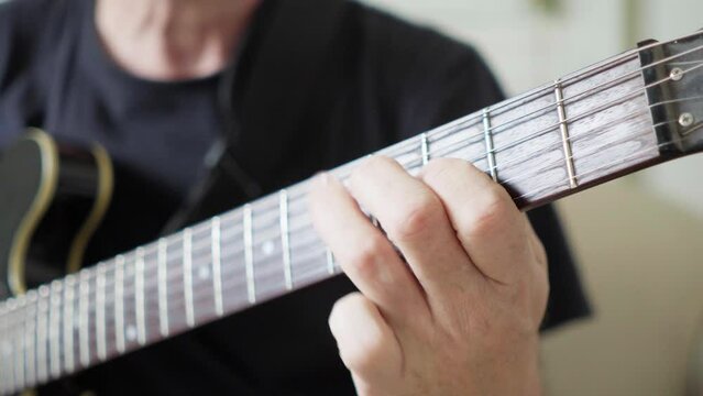 Close-up of a guitarist's left hand improvising on a 335 electric guitar.