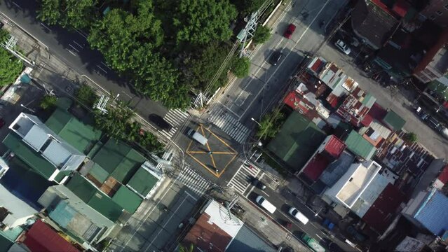 Drone shot of Philippine Road Crossing next to a cemetery and houses with cars passing by