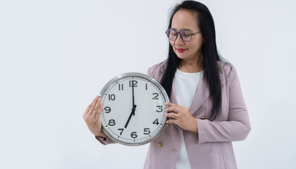 Smiling business Asian woman in eyeglasses holding big clock while looking at the clock