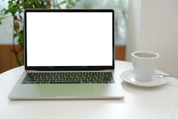 Front view of blank white screen laptop computer with a cup of coffee.