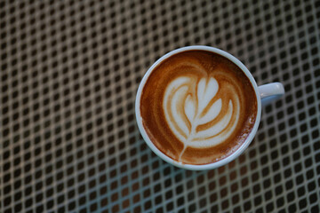 Top view of hot latte coffee with latte art in the white cup. Copy space.