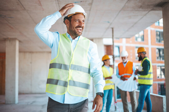 Male construction engineer. Architect with a blueprints at a construction site. Young Man look in camera, building site place background. Portrait of adult male builder, engineer, architect..