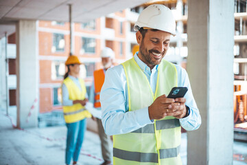 Shot of a young businessman using his smartphone while on a construction site. Portrait of young...