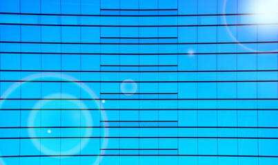 高層ビルのカーテンウォールの壁　ガラス貼りの鏡面に反射する太陽の光とフレア - obrazy, fototapety, plakaty