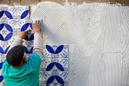 A builder, tiler placing 3 dimension azulejos on adhesive cement, exterior wall, Lagos, Algarve, Portugal, Europe