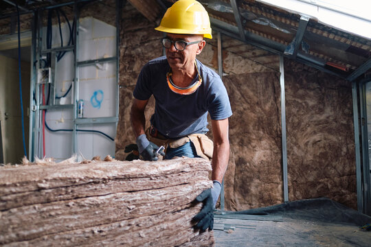 Mature construction worker with stack of insulations at site