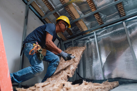 Mature construction worker working with insulation in attic